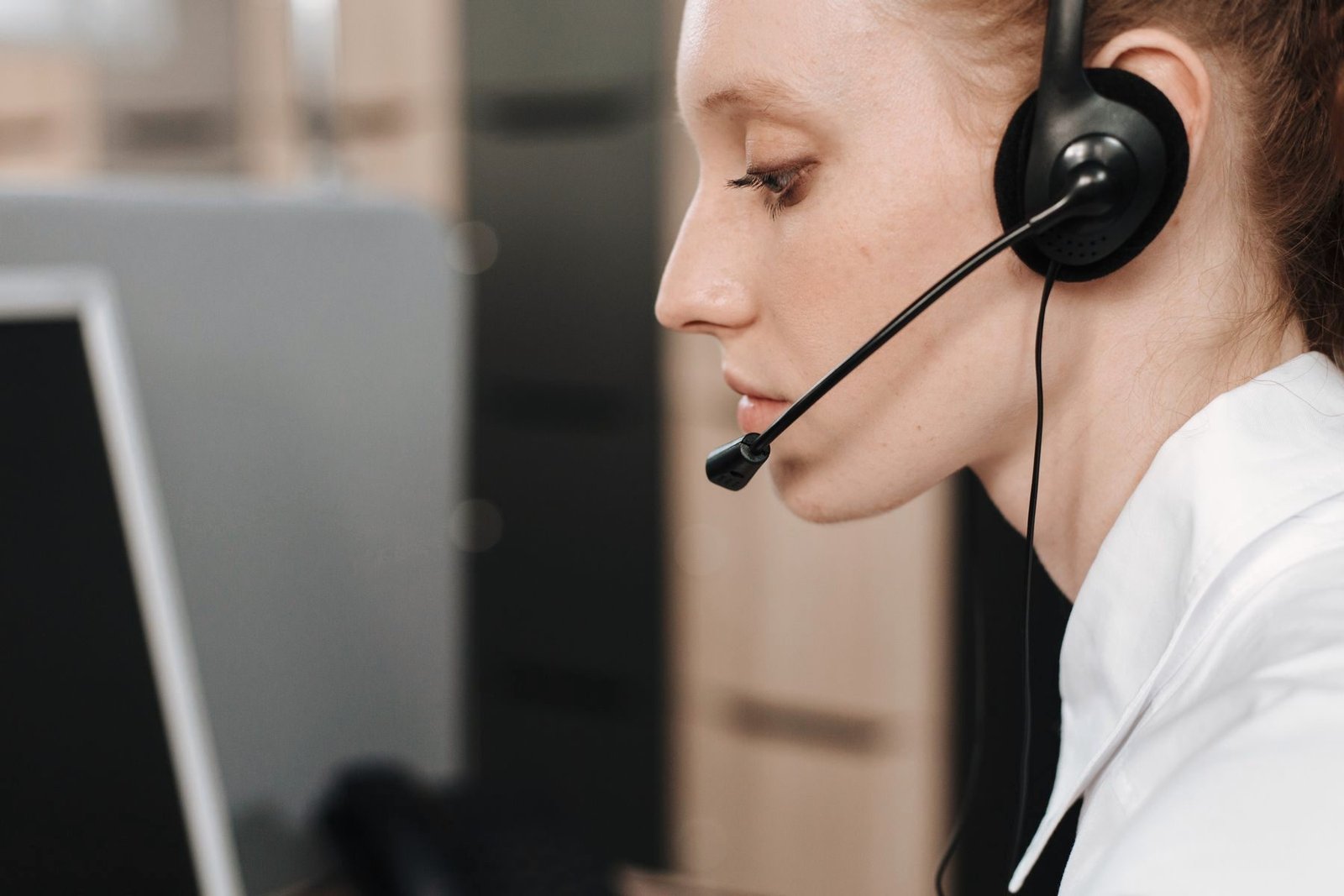 An operator at a desk takes a call on a headset in front of a monitor.