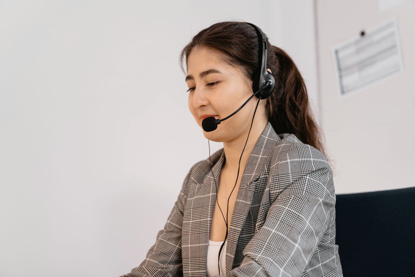 An operator in a blazer takes a call at a bright desk.